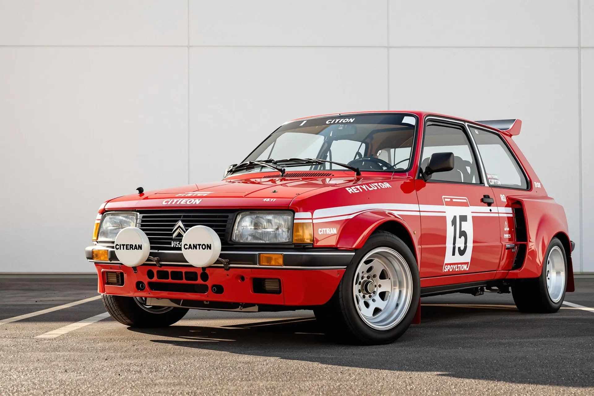 Une Citroën Visa 1000 Pistes rouge parfaitement préservée photographiée de trois-quarts avant, montrant ses caractéristiques élargissements d'ailes et sa posture de rallye distinctive.