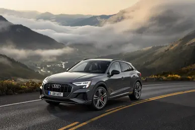 La nouvelle Audi Q3 Sportback 2025 roule sur une route de montagne sinueuse, offrant une vue panoramique sur une vallée embrumée.