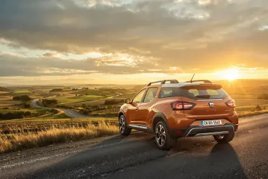 Le SUV Dacia Bigster garé dans un paysage rural français au coucher du soleil.
