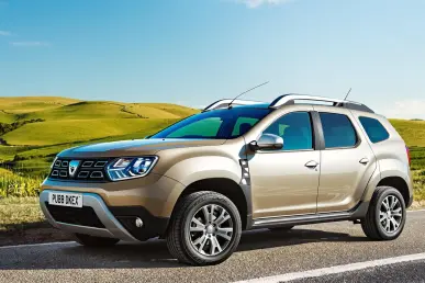 Un Dacia Duster II est garé dans un cadre champêtre avec des collines vertes.