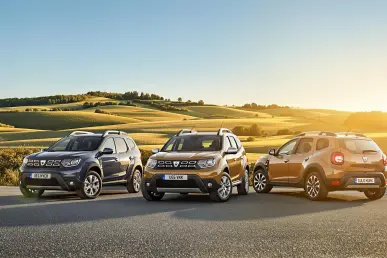 Trois voitures Dacia, Jogger, Duster, et Bigster, stationnées dans la campagne française au coucher du soleil.