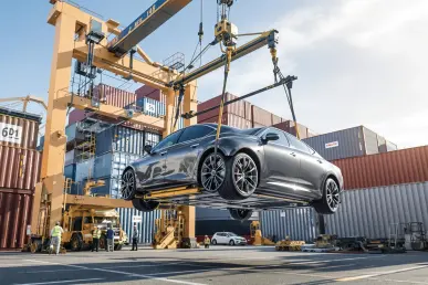 Une voiture moderne est déchargée d'un cargo dans un port français animé.