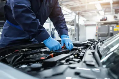 Un technicien examine attentivement la batterie d'une voiture électrique moderne dans un garage.
