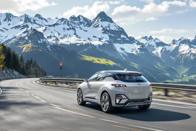 La Kia EV2 roule sur une route sinueuse des Alpes avec montagnes en arrière-plan.