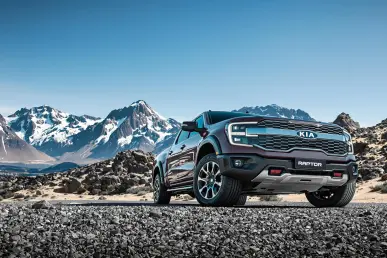 Le Kia Tasman est garé devant un paysage montagneux sous un ciel bleu.