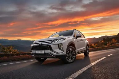 Une Mitsubishi ASX 2025 hybride sur une route de montagne au coucher du soleil.