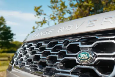 La calandre d'un Range Rover avec le nouveau logo brillant sous un ciel bleu.