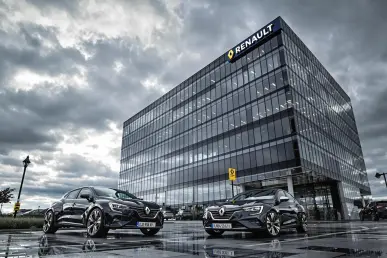 Le siège social de Renault sous un ciel dramatique avec une voiture moderne au premier plan.