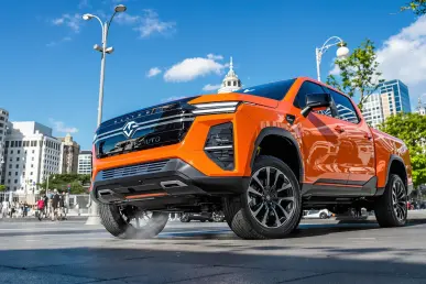 Un pick-up électrique Slate Auto stationné en ville sous un ciel bleu clair.