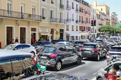 Un conducteur frustré cherche une place de stationnement dans une rue bondée de Marseille avec des voitures garées serrées.
