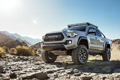 La Toyota Tacoma Trailhunter 2025 sur un terrain rocheux avec montagnes en arrière-plan.
