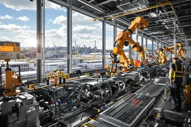 Une usine automobile moderne en France avec des bras robotiques en action sous un ciel lumineux.