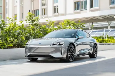 Une voiture électrique moderne stationnée avec des panneaux solaires en arrière-plan, sous un ciel ensoleillé.