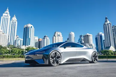 Une voiture électrique futuriste stationnée devant une ville animée sous un ciel bleu.