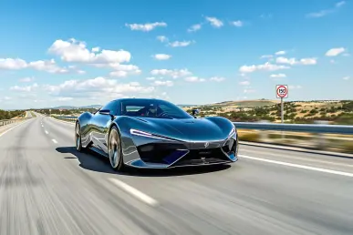 Une voiture moderne roule rapidement sur une autoroute espagnole sous un ciel bleu.