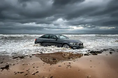 Une voiture moderne bloquée sur une plage, partiellement submergée par la marée montante.