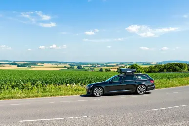 Une voiture moderne avec radar sur une route de campagne française sous un ciel bleu.