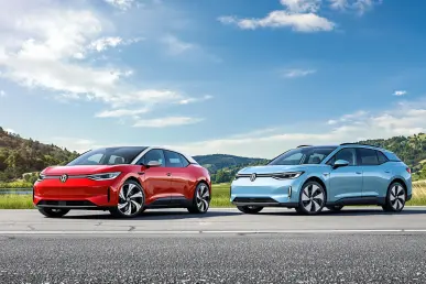 Deux Volkswagen ID.4 et ID.5 garées sur une route pittoresque avec ciel bleu et verdure.