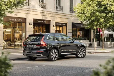 La Volvo XC60 restylée est stationnée dans un cadre urbain chic, entourée de boutiques de luxe.